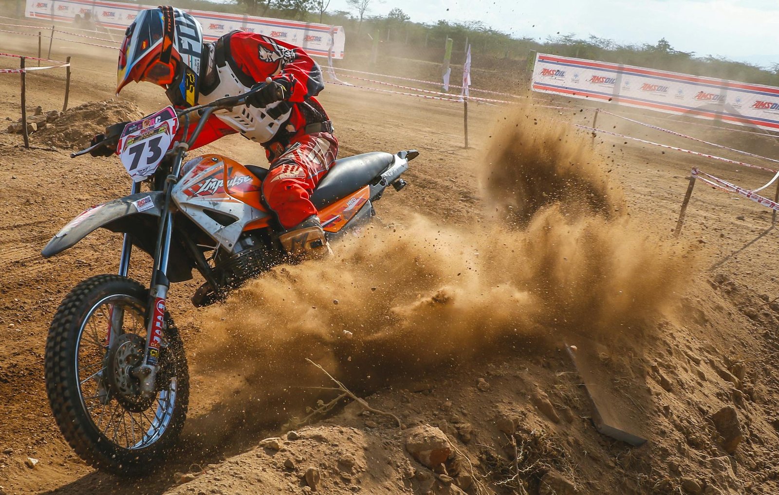 Dynamic motocross scene with rider kicking up dust on a dirt track.